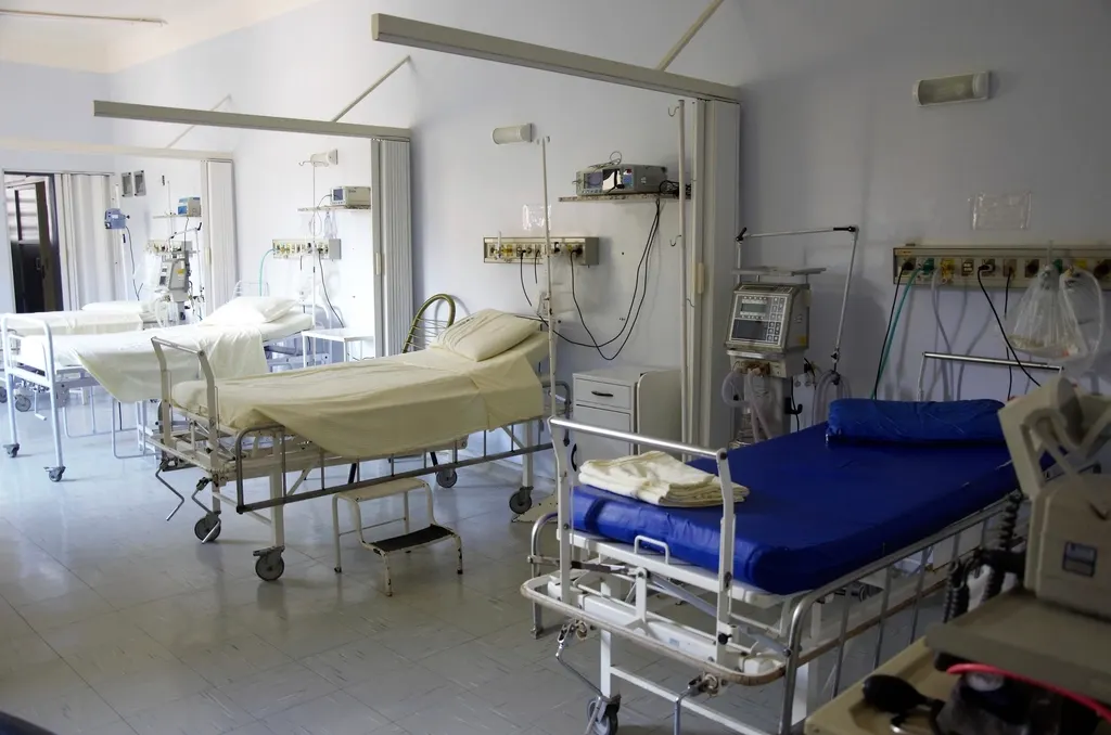 An empty hospital ward with beds and bedside monitors.